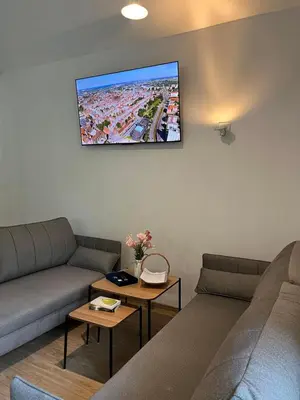 a living room with two couches and a tv on the wall at Dom nad Stryszawką z SAUNĄ - domek wypoczynkowy in Stryszawa