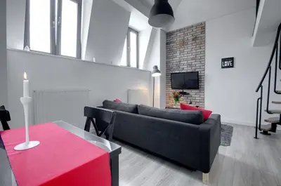a living room with a black couch and a red table at Apartament Romantyczny Zamkowa15 in Kraków