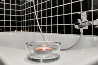 a candle in a glass bowl on a bath tub at Apartament Romantyczny Zamkowa15 in Kraków