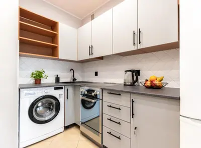 a kitchen with white cabinets and a washer and dryer at Lubomirskiego 9 in Kraków