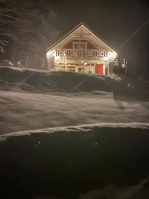 a house with lights on the front of it in the snow at Forest house in Targanice