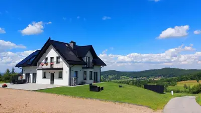 a white house with a black roof on a hill at Zasankowe Wzgórze in Zasań
