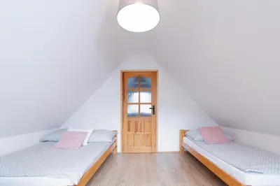 two beds in a room with a door at Kamyczkowy domek w Zawoi in Zawoja