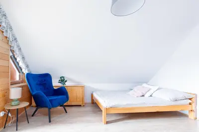 a bedroom with a bed and a blue chair at Kamyczkowy domek w Zawoi in Zawoja