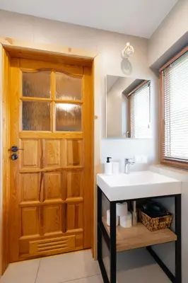 a bathroom with a sink and a wooden door at Kamyczkowy domek w Zawoi in Zawoja