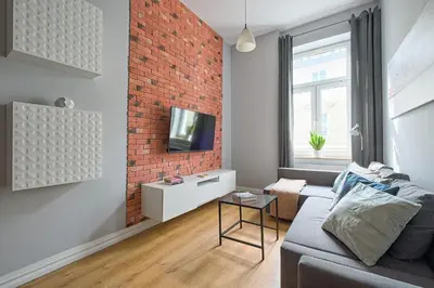 a living room with a couch and a brick wall at Urban Nest Apartments Krakowska 10 in Kraków