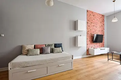 a white room with a bed and a brick wall at Urban Nest Apartments Krakowska 10 in Kraków