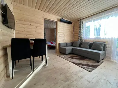 a kitchen with wooden walls and a table and a sink at Domek wypoczynkowy Górskie Zacisze in Sidzina