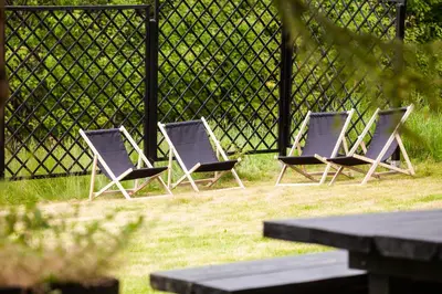 three chairs sitting in the grass next to a fence at Dom na Wielkiej Polanie in Sidzina