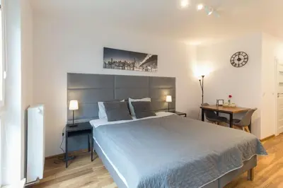 a bedroom with a bed and a desk and a clock at Zabłocie Harmony Studio B in Kraków