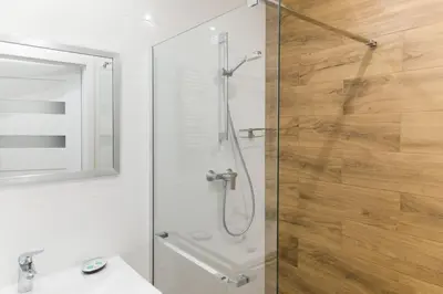 a bathroom with a shower with a glass door at Zabłocie Harmony Studio B in Kraków