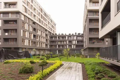 an apartment complex with a garden in front of a building at Zabłocie Harmony Studio B in Kraków