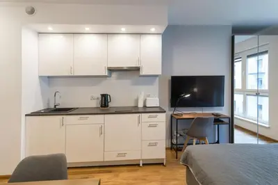 a kitchen with white cabinets and a table and a bed at Zabłocie Harmony Studio B in Kraków