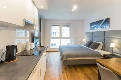 a bedroom with a large bed and a kitchen at Zabłocie Harmony Studio B in Kraków