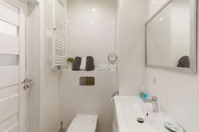 a white bathroom with a sink and a mirror at Zabłocie Harmony Studio B in Kraków
