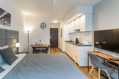 a bedroom with a bed and a desk and a kitchen at Zabłocie Harmony Studio B in Kraków