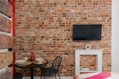 a brick wall with a table and chairs and a tv at Malila Premium Apartments Cracow Centre Starowiślna 41 in Kraków