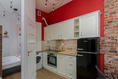 a kitchen with a black refrigerator and a brick wall at Malila Premium Apartments Cracow Centre Starowiślna 41 in Kraków