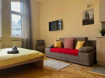 a kitchen with wooden cabinets and a sink and a couch at Cheerful Corner in Kraków