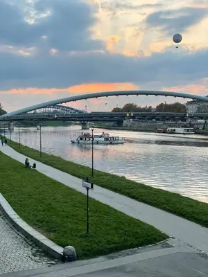 a bridge over a river with boats on the water at Elegant Riverside Flat Garden in Kraków