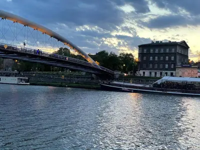 a bridge over a river with a building in the background at Elegant Riverside Flat Garden in Kraków