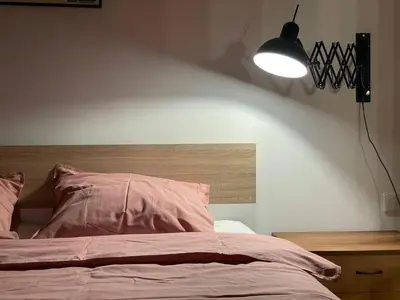 a bedroom with a bed with a light on the wall at Elegant Riverside Flat Garden in Kraków