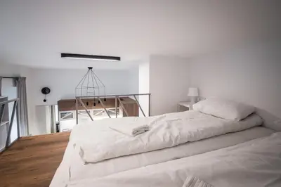 a white bedroom with a large bed and a staircase at Old Railway Station view Lubicz Residence WAWELOFTS in Kraków