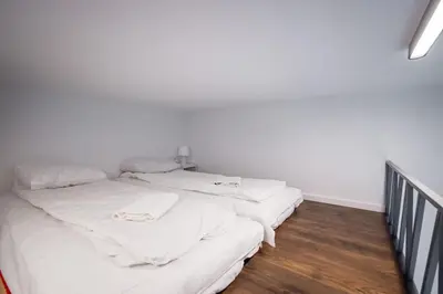 two beds in a room with white walls and wood floors at Old Railway Station view Lubicz Residence WAWELOFTS in Kraków