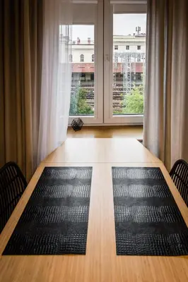 a dining room table with a large window and a black rug at Old Railway Station view Lubicz Residence WAWELOFTS in Kraków