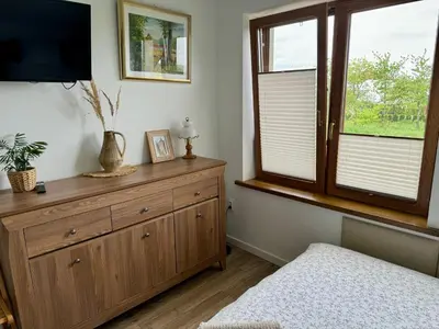 a bedroom with a dresser with a tv and a window at Noclegi DobraNocka in Sąspów