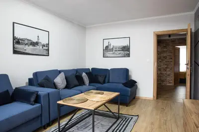 a living room with a blue couch and a table at Apart Dwudziestolecie in Wadowice