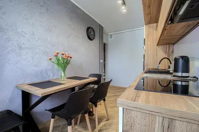 a kitchen with a table with chairs and a vase of flowers at Apart Dwudziestolecie in Wadowice