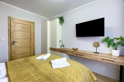 a bedroom with a bed and a flat screen tv at Apart Dwudziestolecie in Wadowice