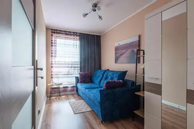 a living room with a blue couch and a window at Nowy apartament - Bulwary nad Sołą - 52m2 in Oświęcim