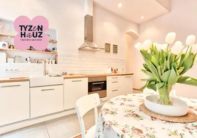 a white kitchen with a table with a vase of flowers at Zacisze Street in Kraków