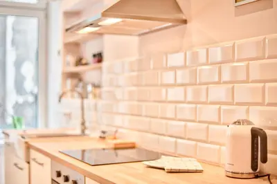 a kitchen with white tiled walls and a sink at Zacisze Street in Kraków