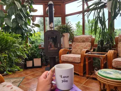 a person holding a coffee cup in a room with a stove at Brzozowy Zakątek in Bochnia