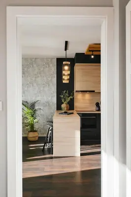 a kitchen with black and wooden cabinets and a counter at Vermelo Boho Apartment in Kraków