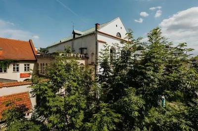 a white building with trees in front of it at Plac Nowy Panorama Old Town View on Kazimierz in Kraków