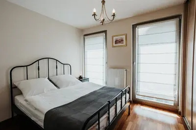 a bedroom with a large bed and two windows at Plac Nowy Panorama Old Town View on Kazimierz in Kraków