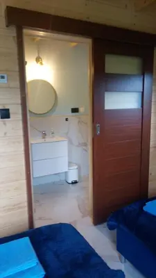 a bedroom with a bathroom with a sink and a door at Cztery Pory Roku pokoje z łazienkami do wynajęcia in Osiek