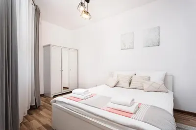 a white bedroom with a large bed with towels on it at City of the Kings-Camomile Apartment in Kraków