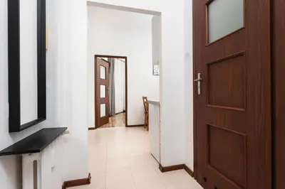 a hallway with a wooden door and a tile floor at City of the Kings-Camomile Apartment in Kraków