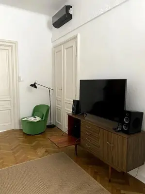 a living room with a television and a green chair at In the heart of old town in Kraków