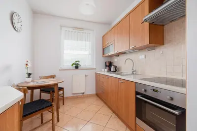 a kitchen with wooden cabinets and a table and a sink at Cozy Apartment with Balcony Chmieleniec by Noclegi Renters in Kraków
