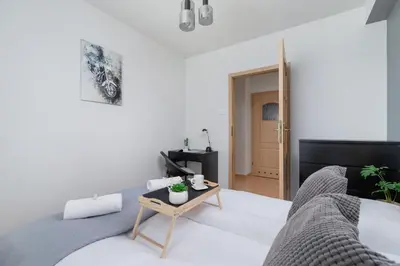 a white bedroom with a bed and a table at Cozy Apartment with Balcony Chmieleniec by Noclegi Renters in Kraków