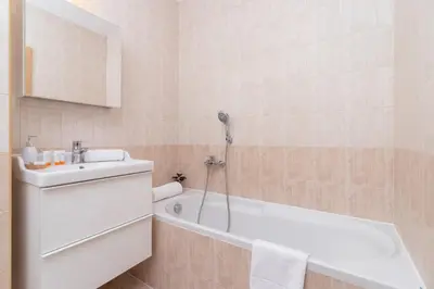 a bathroom with a white tub and a sink and a bath tubermott at Cozy Apartment with Balcony Chmieleniec by Noclegi Renters in Kraków
