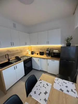 a small kitchen with white cabinets and a table with a tableablish at Apartament Jaśminowa in Chrzanów