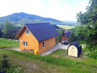 a small house with a blue roof and a garage at Domek Na Przełęczy in Wierzbanowa