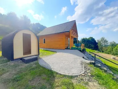 a small wooden cabin with a driveway next to a field at Domek Na Przełęczy in Wierzbanowa